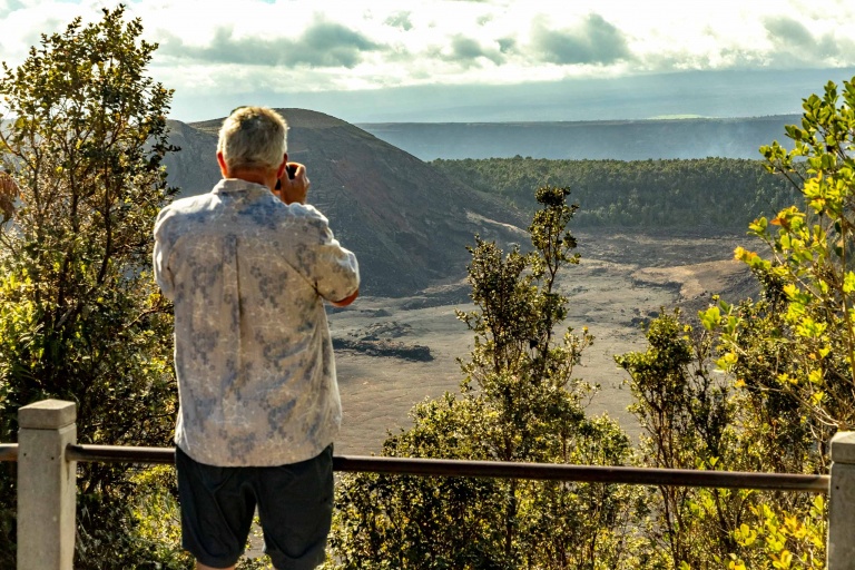 A visitor stands at an overlook of a Hawaiian volcanic caldera