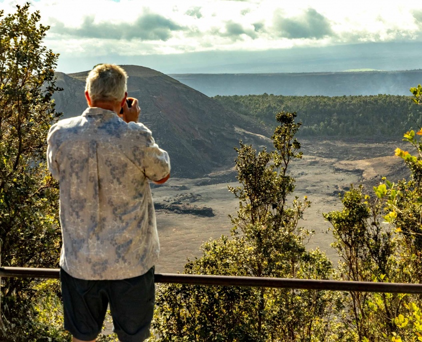 A visitor stands at an overlook of a Hawaiian volcanic caldera